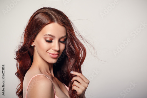 Studio glamor portrait of a beautiful woman with luxurious hair on a light background.