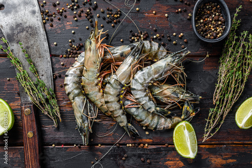 Fresh tiger shrimps, prawns with spices and herbs. Black woodenbackground. Top view