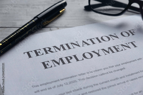 Selective focus of pen,glasses and Termination of Employee letter on a white wooden background.