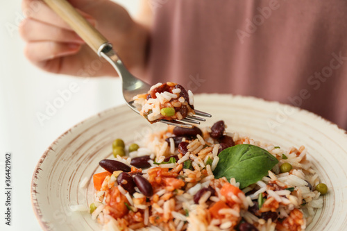 Woman eating tasty rice with beans and vegetables, closeup