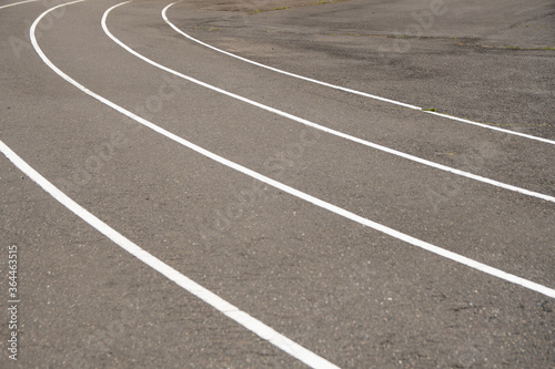 white markings for running in a sports stadium. outdated asphalt pavement at the stadium.