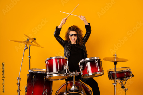 Photo of popular rocker redhair lady plays instruments beat raise hands drum sticks concert sound check repetition wear black leather outfit sun glasses isolated yellow background