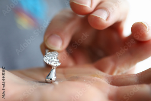 Male hand holding piece of liquid gallium