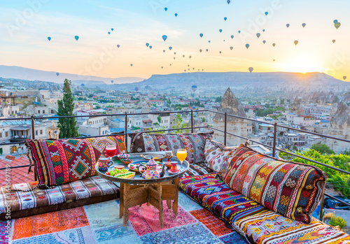 Traditional turkish breakfast with Cappadocia view and flying balloons on the background. Goreme, Turkey..