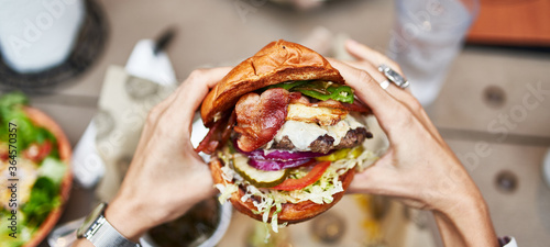 holding huge sloppy cheeseburger in hands shot from pov