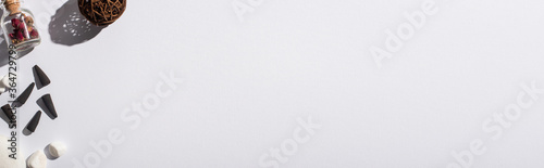 top view of black incense cones, stones, aroma flowers and decorative ball on white background, panoramic shot