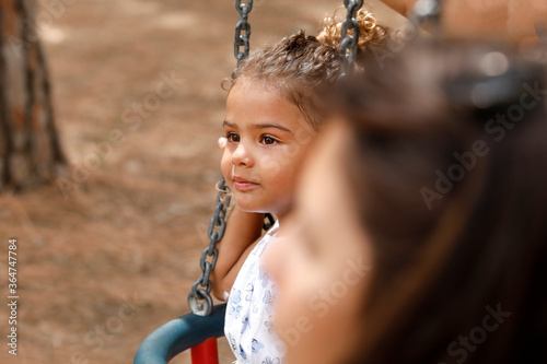 ritratto stretto di una bambina scura di carnagione di origine brasiliana che gioca su un altalena