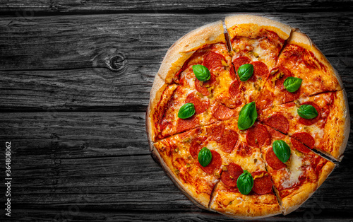 Pepperoni Pizza with Mozzarella cheese, salami, Tomato sauce, pepper, Spices and Fresh basil. Italian pizza on wooden table background