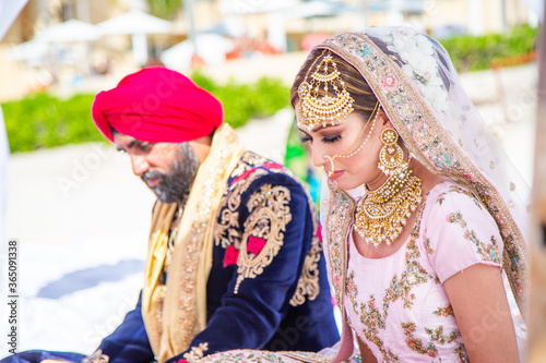 Sikh bride and groom next to each other during marriage ceremony in traditional wedding attire