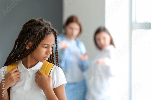 Pupils bullying African-American girl at school. Stop racism