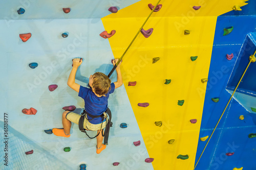 6 years old child climbing on a wall in a climbing center