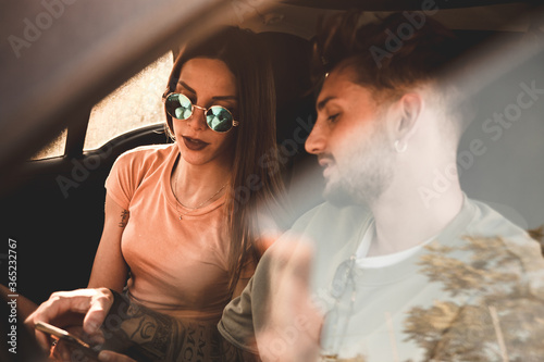 Momento di relax con il telefono di una giovane coppia di fidanzati nella loro auto mentre sono in viaggio per le vacanze estive