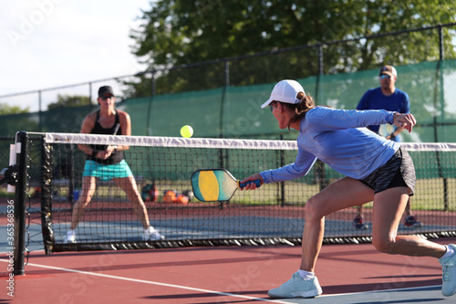 A woman hits a dink shot while playing pickleball.