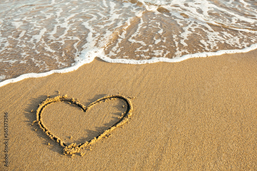 Drawn Heart on the sand of a sea tropical beach.