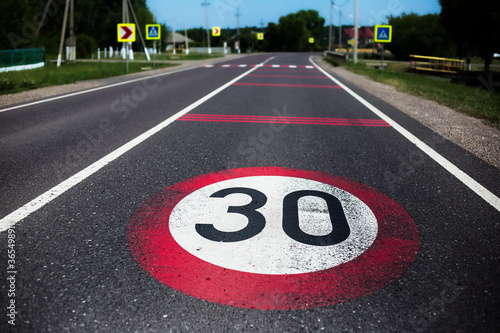 30km/h speed limit sign painted on asphalting road.