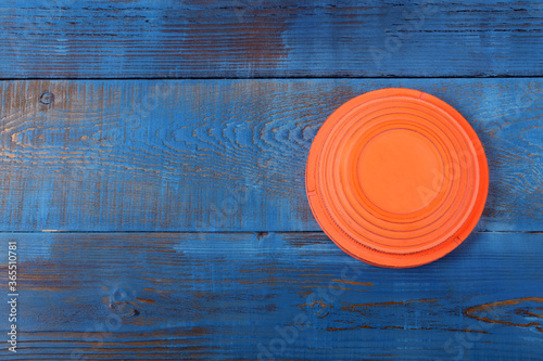 Orange flying target plate against the blue wooden background 