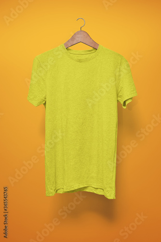 Yellow T-Shirt on a hanger against an orange background