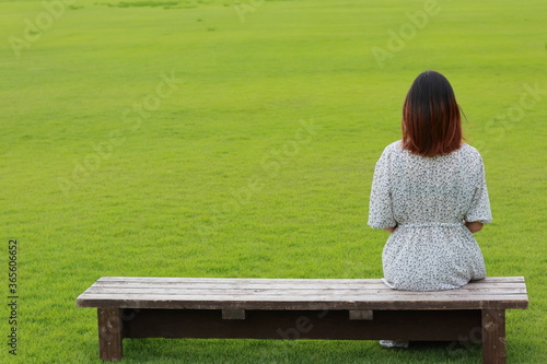 芝生でベンチに座る女性