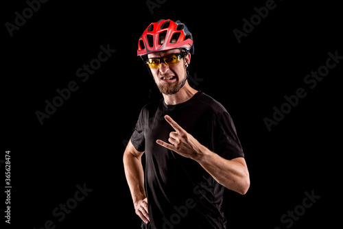 Portrait of a cyclist in a bright helmet and glasses isolated on a black background.