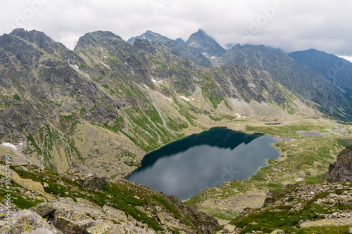 Scenic view of mountains clouds and green with a reflection in a frogs lake. Stony shore. hlincovo pleso. hlincovo lake. High Tatras, Slovakia Concept of nature and tourism