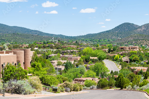 Cityscape view in Santa Fe, New Mexico mountains of road street through community neighborhood with green plants summer and adobe traditional houses
