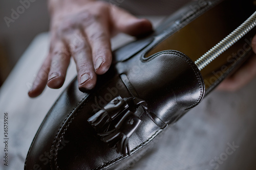 Young caucasian man repairing old male leather shoes.