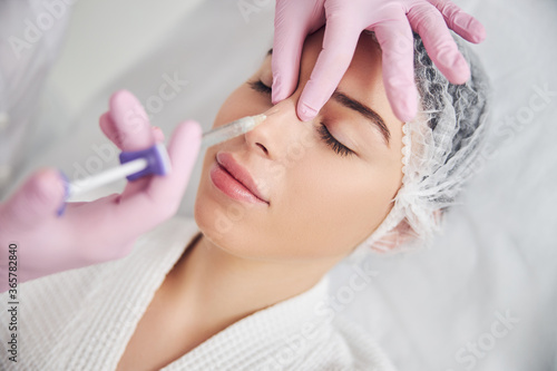 Calm female patient undergoing injectable beauty procedure