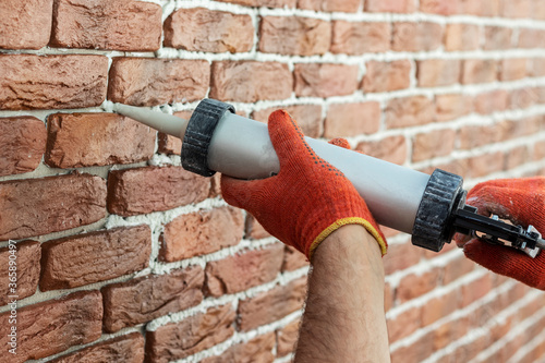 Applying grout with a syringe. Grouting decorative tile with white cement grout.