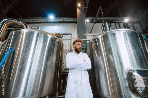  Portrait of professional caucasian handsome technologist expert in white uniform standing in pharmaceutical or food factory - production plant