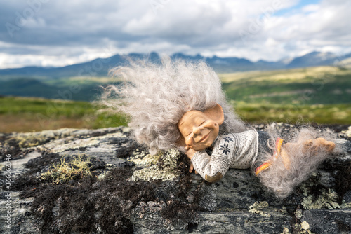 Beautiful peaceful and sleeping troll girl figure relaxing outdoors with mountain scenery in the background.