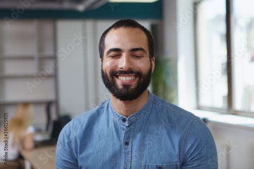 Close up of a handsome cheerful male entrepreneur smiling with his eyes closed