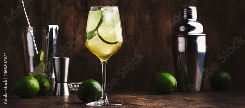 Mojito cocktail with lime and mint in wine glass on wooden background. Panoramic banner with copy space