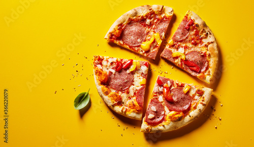 Sliced pepperoni pizza on yellow with copyspace