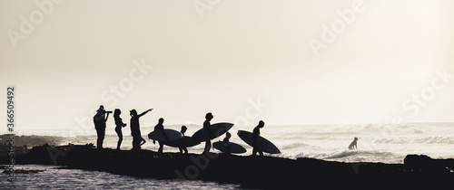 group of people having fun together entering to the water at the beach to surfing - surfers enjoying summer and ocean - vacations and holiday or journey concept