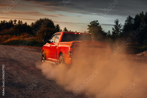 Pickup truck car in motion at country road with clouds of dust