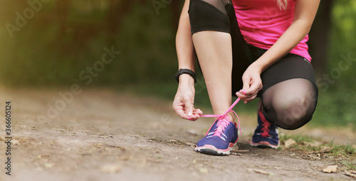 Young fitness woman tying shoelace running sneakers. Healthy fit living.