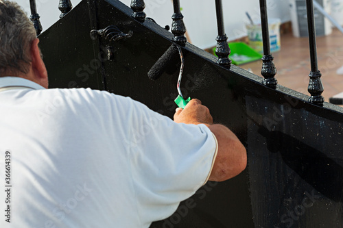 Hombre pintando reja de hierro.