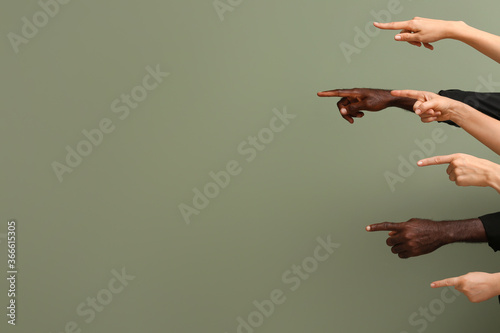 Hands of Caucasian women and African-American man showing something on color background. Racism concept