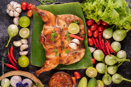 Grilled chicken on a plate with chili peppers, garlic sauce and sprinkled with pepper seeds.