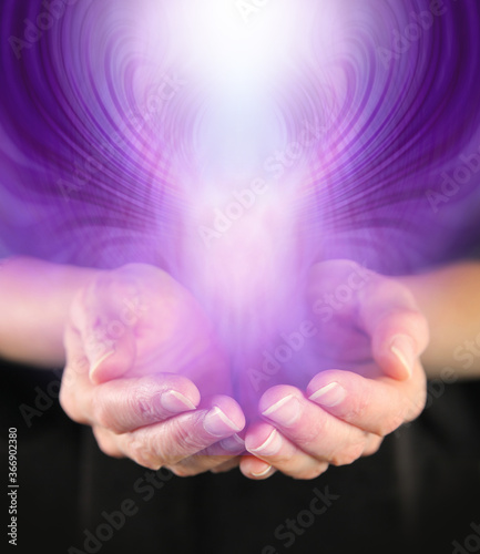 Demonstration of Paranormal Activity - cupped hands with a purple entity rising up and outwards and space for copy 