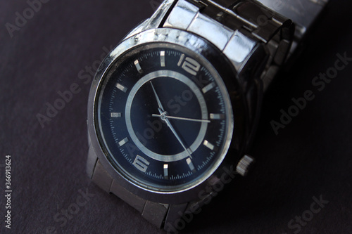 Wrist watch isolated on dark background. Selective focus on number six on watch dial.