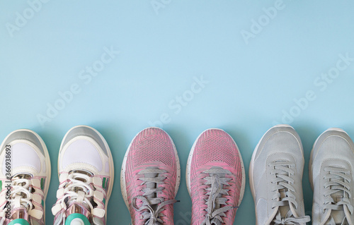 Three pair of sport shoes top view on light blue background with copy space
