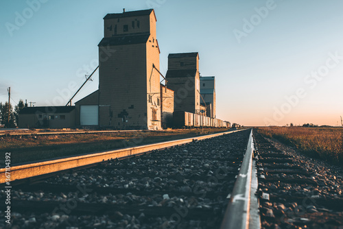 Grain silos and railway tracks running past them at sunrise 