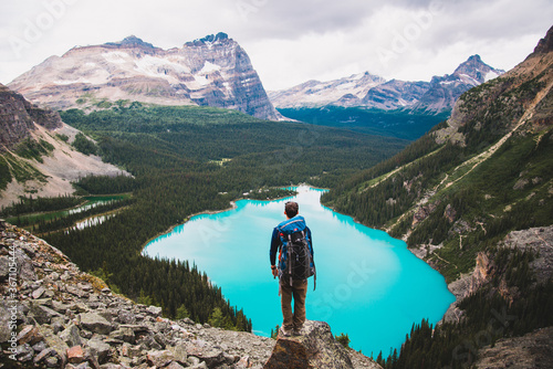 Hiker overlooking alpine lake in mountains 