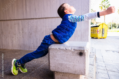 Brave boy with gesture of impetuousness and empowerment playing in the city.