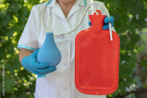 Nurse hold blue enema and red enema bag. Medical Gastrointestinal Colon Background Concept. Intestines cleansing procedure constipation.