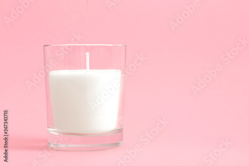 White wax candle in glass Isolated on pastel pink background, mock up