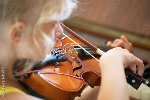 little girl with concentration playing a small violin, suzuki lessons, horizontal shape, music lesson