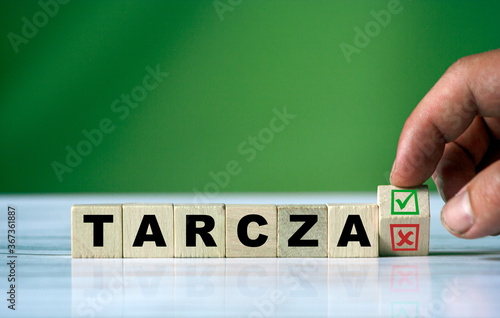 hand turns the wooden cube and changes the polish word TARCZA (english shield)
