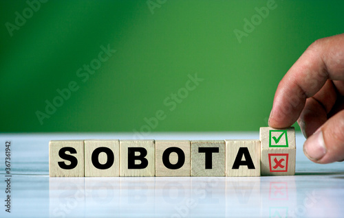 hand turns the wooden cube and changes the polish word SOBOTA (english saturday)